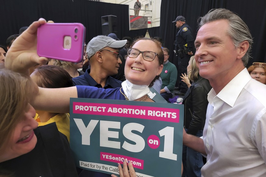 Le gouverneur démocrate de la Californie, Gavin Newsom, à droite, prend des selfies avec ses partisans.