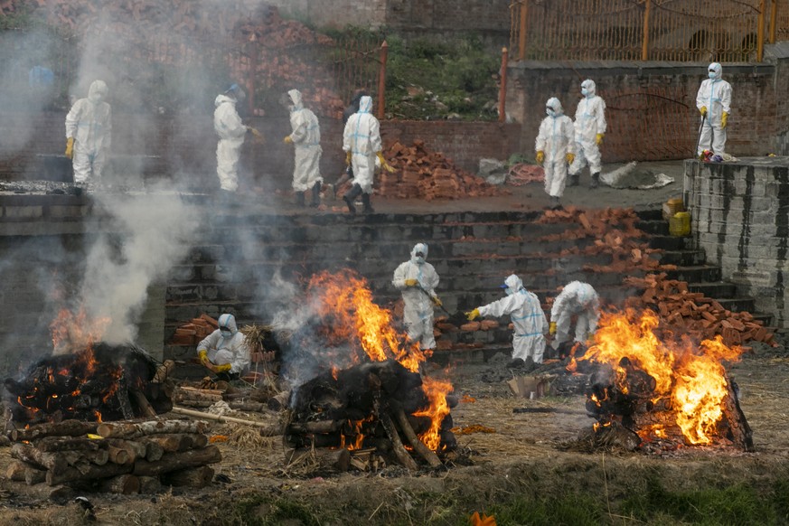 Nepalese men in personal protective suits cremate the bodies of COVID-19 victims as others extend the crematorium as number of deaths rise near Pashupatinath temple in Kathmandu, Nepal, Wednesday, May ...