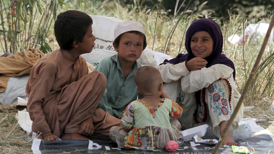 Displaced children sit under their tent&#039;s shade as they take refuge on a roadside after fleeing their flood-hit homes, in Charsadda, Pakistan, Monday, Aug. 28, 2022. International aid was reachin ...