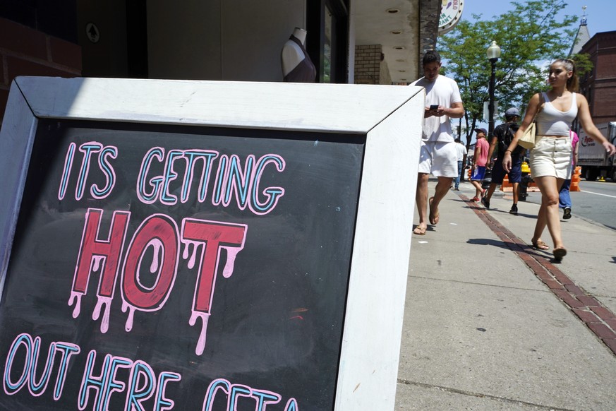 With temperatures hovering in the mid-90&#039;s, people walk near a sign down Hanover Street in the North End, during a summer heat wave, Thursday, July 21, 2022, in Boston. Dangerously high temperatu ...