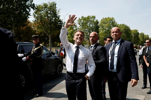epa13110531 French President Emmanuel Macron (L) waves to members of the public as he leaves after the annual Bastille Day military parade on the Place de la Concorde in Paris, France, 14 July 2026. F ...