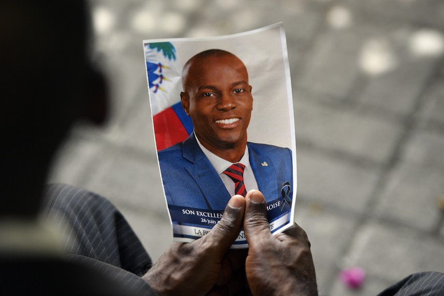 FILE - A person holds a photo of late Haitian President Jovenel Moise during his memorial ceremony at the National Pantheon Museum in Port-au-Prince, Haiti, July 20, 2021. Authorities say a former Hai ...
