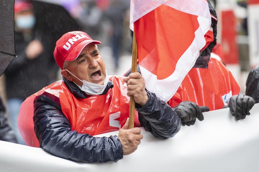 Des manifestants avec des pancartes et des drapeaux defilent dans les rues de Geneve, lors du defile du 1er mai - Fete du Travail, ce samedi 1 mai 2021 a Geneve. Le traditionnel cortege du 1er mai, pl ...