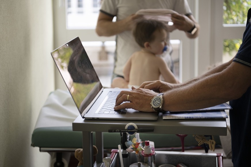 A pediatrician at the Lindenpark Children&#039;s Medical Centre uses a laptop to record the results of an examination of an infant in an electronic patient record, photographed on 26 July 2019 in Baar ...