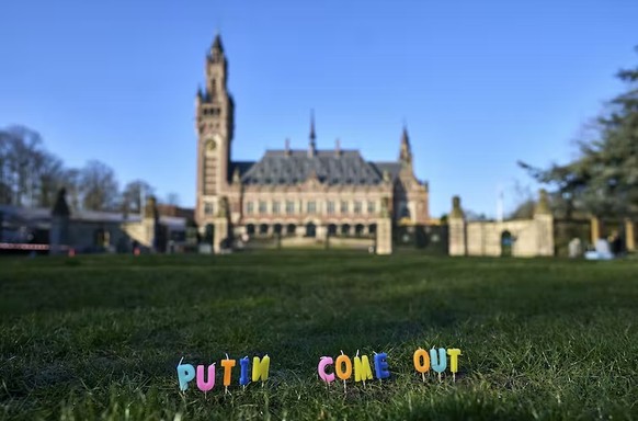 Des bougies sont plantées dans l’herbe avec l’inscription Putin Come Out devant la Cour pénale internationale à La Haye, aux Pays-Bas, en mars 2022.