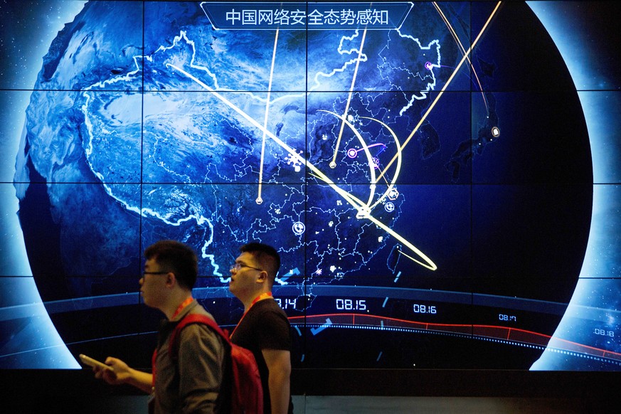 FILE - Attendees walk past an electronic display showing recent cyberattacks in China at the China Internet Security Conference in Beijing, on Sept. 12, 2017. Hackers linked to China were likely behin ...