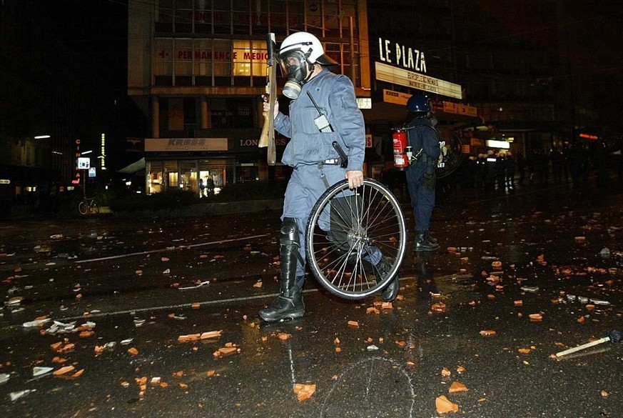 A policeman carries a wheel of a bicycle destroyed during clashes with demonstrators in Geneva, Monday 02 June 2003. Police used tear gas and water canons to disperse a group of protesters on Monday e ...