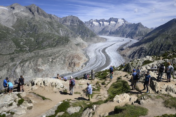 Peoples watch the view of the Swiss Aletsch glacier, the longest glacier in Europe, from the viewpoint Mossfluh, next to Bettmeralp, Switzerland, Thursday, July 14, 2022. The Aletsch Glacier, a river  ...