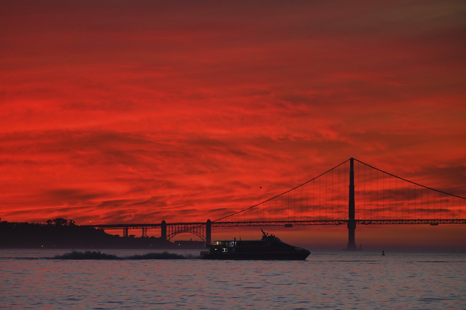 A ferry boat travels across the water as the setting sun illuminates the Golden Gate Bridge as seen from Treasure Island, Friday, Jan. 14, 2022, in San Francisco. (Jose Carlos Fajardo/Bay Area News Gr ...