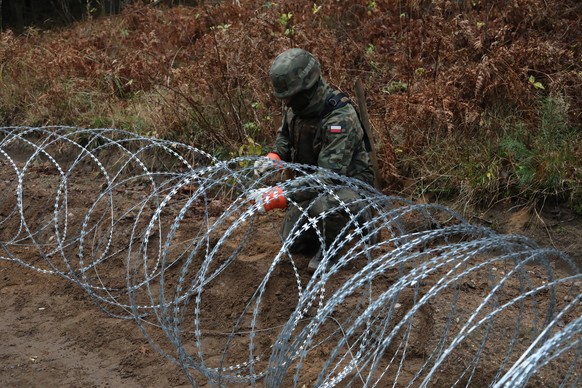 epa10308453 A Polish soldier installs a barbed wire along Polish border with the Russian exclave of Kaliningrad, near Szyliny village, north-eastern Poland, 16 November 2022. Polish Defence Minister M ...