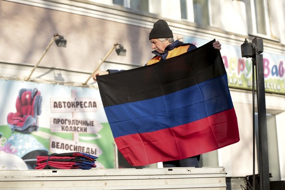 A municipal worker prepares to put up a Donetsk People Republic flag on a building in Donetsk, the territory controlled by pro-Russian militants, eastern Ukraine, Monday, Feb. 21, 2022. World leaders  ...