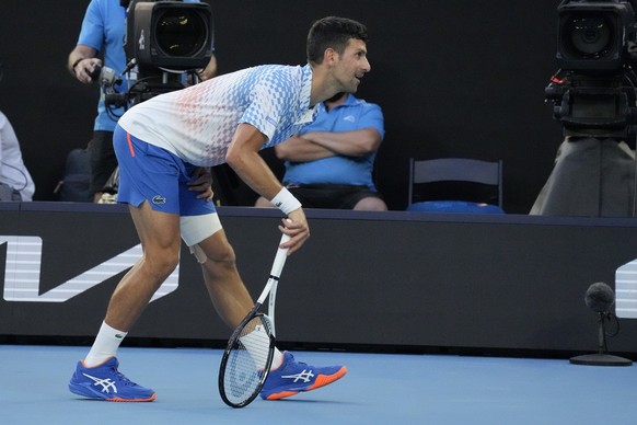 Novak Djokovic of Serbia stretches his injured leg during his fourth round match against Alex de Minaur of Australia at the Australian Open tennis championship in Melbourne, Australia, Monday, Jan. 23 ...
