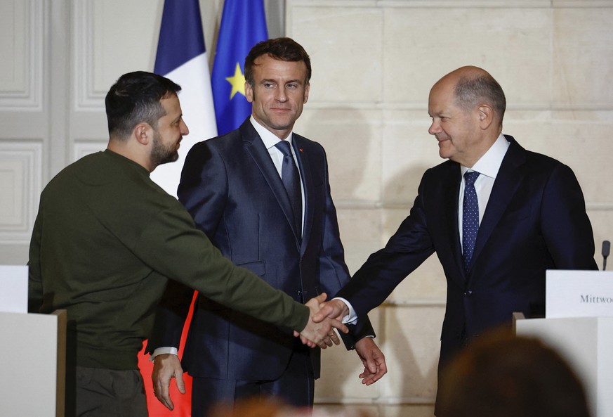 FILE - Ukrainian President Volodymyr Zelenskyy, left, shakes hands with German Chancellor Olaf Scholz, as French President Emmanuel Macron looks on while they attend a joint press conference at the El ...