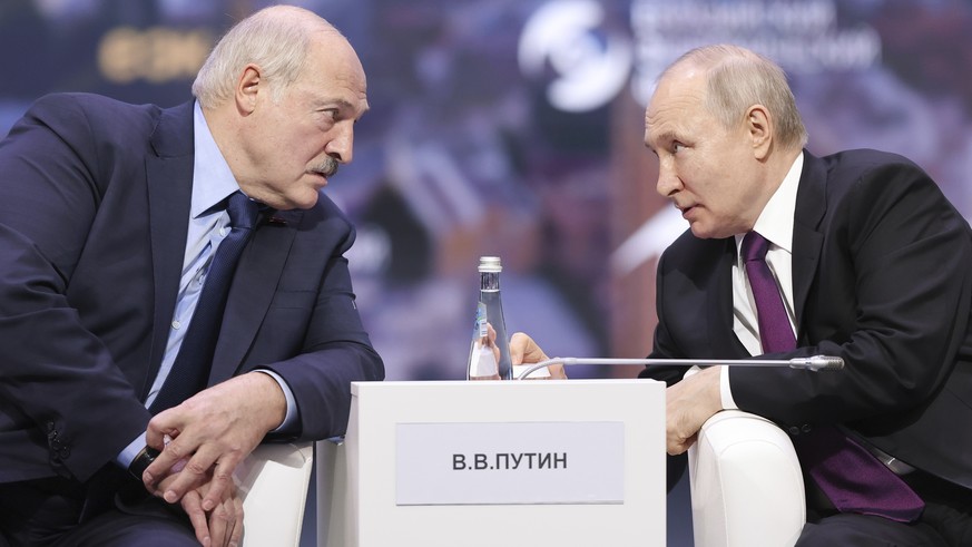 In this photo released by Roscongress Foundation, Russian President Vladimir Putin, right, and Belarusian President Alexander Lukashenko talk to each other during the plenary session of the Eurasian E ...