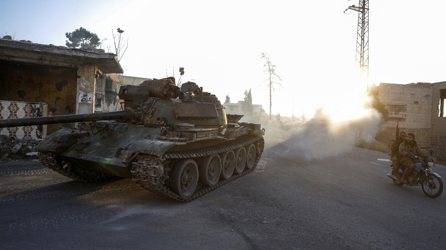 Syrian opposition fighters drive a motorcycle and an armoured vehicle seized from the Syrian army in the town of Maarat al-Numan, south of Idlib, Syria, Tuesday Dec. 3, 2024.(AP Photo/Omar Albam)