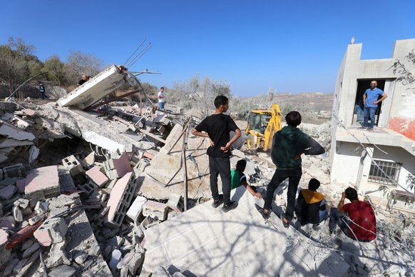 epa10950544 Palestinians gather to inspect the rubble at the site of the demolished family home of a Hamas leader Saleh al-Arouri, in the West Bank village of Arura, northwest of the west bank city of ...