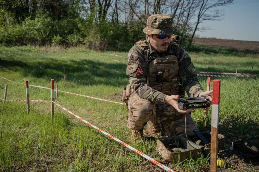 Serhiy Slavinsky, inspecteur du service des explosifs de la police nationale, montre un dispositif utilisé pour faire exploser des mines terrestres dans un champ de mines près du village de Korobochki ...
