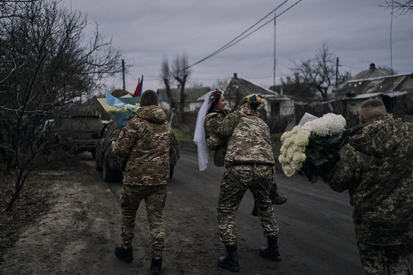 Ukrainian army medic Oleksander carries his bride and comrade Eugenia after their wedding ceremony in Lyman, Donetsk region, Ukraine, Saturday, Dec. 24, 2022. (AP Photo/Felipe Dana)