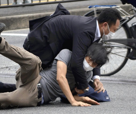 Tetsuya Yamagami, bottom, is detained near the site of gunshots in Nara Prefecture, western Japan, Friday, July 8, 2022. Former Japanese Prime Minister Shinzo Abe, a divisive arch-conservative and one ...