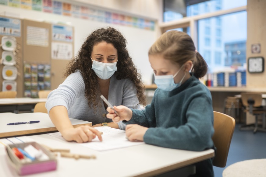Klassenlehrperson Tania Martinez und eine Schuelerin tragen Hygienemasken, um sich und andere gegen eine Uebertragung des Coronavirus zu schuetzen, in einem Schulzimmer der Schule Pfingstweid in Zueri ...