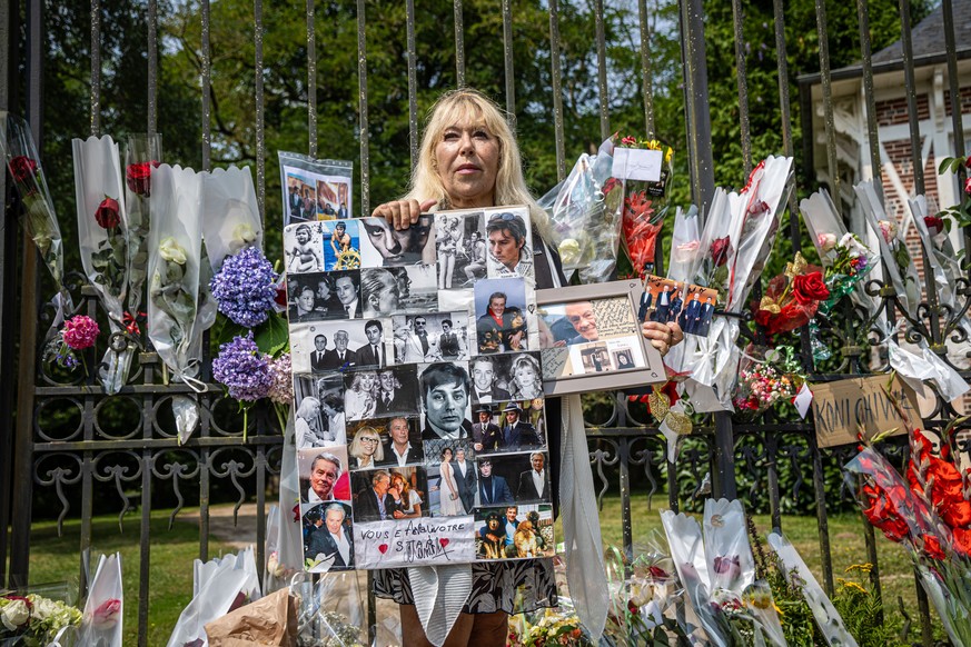 epa11554986 Isabelle, a fan of the late French actor Alain Delon, poses with pictures of Delon in front of the gate of his property as villagers and fans gather to pay their tribute in Douchy, France, ...
