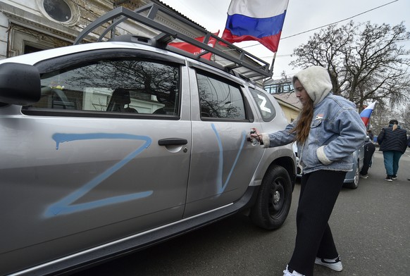 epa10530210 A girl paints the letters Z and V, symbols of support for Russian troops, onto a car on the ninth anniversary of Russia&#039;s annexation of Crimea in Simferopol, Crimea, 18 March 2023. Ru ...