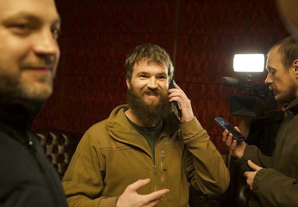 In this photo provided by the Ukrainian Interior Ministry Press Office, Azov officer Sviatoslav Palamar, center, who was released in a prisoner exchange between Russia and Ukraine, speaks on the phone ...