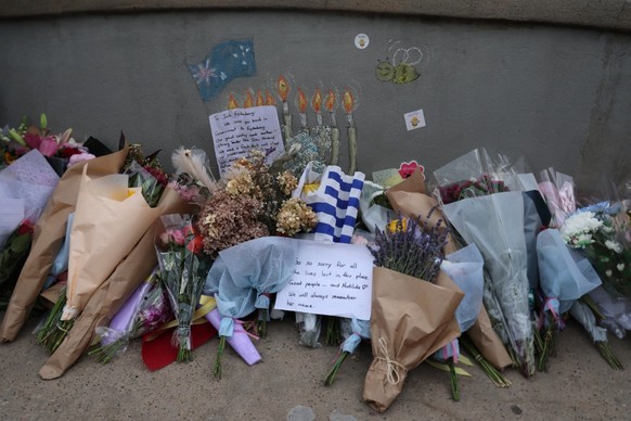 Floral tributes and a note are laid for victims on a small bridge where gunmen had stood during a mass shooting in Bondi Beach, in Sydney on December 21, 2025. (Photo by DAVID GRAY / AFP)