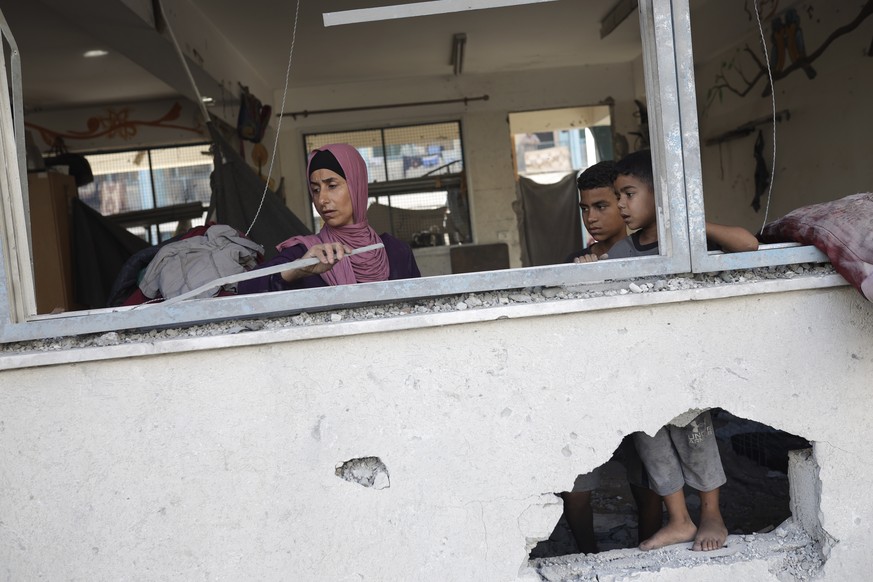 A Palestinian family inspects heavy damage to a UNRWA school sheltering displaced persons the day after a nearby house was targeted by Israeli bombardment in Khan Younis, southern Gaza Strip, Friday,  ...