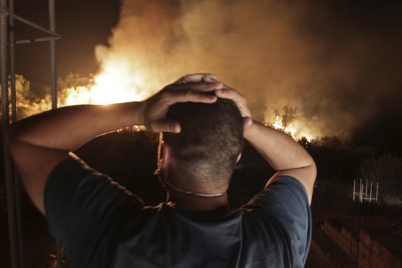 In this photo taken Wednesday, Aug.11, 2021, a man looks at a forest fire near the village of Larbaa Nath Irathen, neat Tizi Ouzou, in the mountainous Kabyle region, 100 kilometers (60 miles) east of  ...