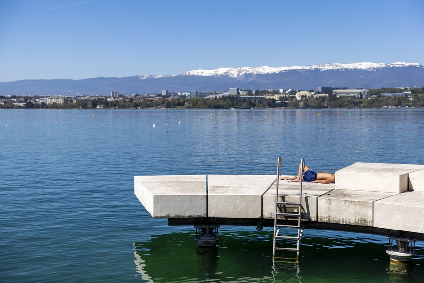 Un homme prend un bain de soleil sur un ponton de baignade sur le quai de Cologny, sur les rives du lac Leman, lors d'un episode de temperatures anormalement douces pour la saison, ce mercredi 8  ...