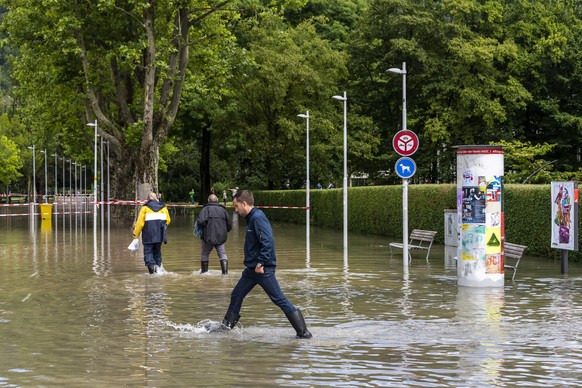epa09348753 People walk in the lake water in the harbor as the water level of the Bielersee rose following heavy rainfall over the past few days in Biel, Switzerland, 16 July 2021. The water level of ...