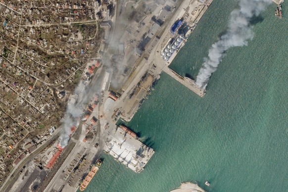 In this satellite photo from Planet Labs PBC, a Ukrainian naval vessel and a nearby building burn in the besieged city of Mariupol, Ukraine, Wednesday, April 6, 2022. The photo appears to show the Ukr ...