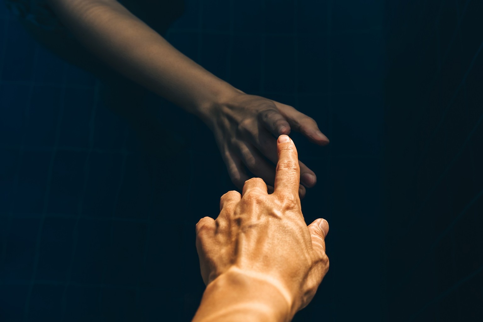 A woman&#039;s hand touches another hand underwater. The concept of life and death, a living person and artificial intelligence.