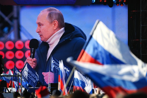 Russian President Vladimir Putin is seen on a big screen as he delivers his speech at the concert marking the eighth anniversary of the referendum on the state status of Crimea and Sevastopol and its  ...