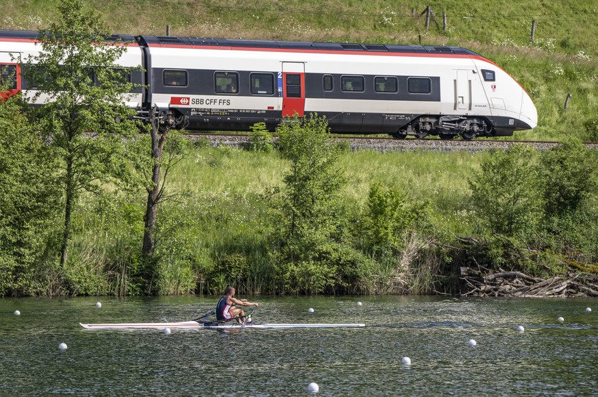 Ein Ruderer aus Daenemark beim Training sowie ein Zug der SBB auf Vorbeifahrt am Rotsee anlaesslich des Ruder Weltcups auf dem Rotsee in Luzern am Mittwoch, 22. Mai 2024. (KEYSTONE/Urs Flueeler)