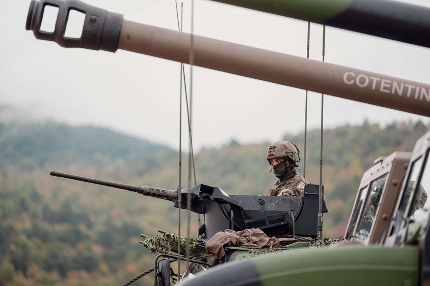 Un soldat du 35e régiment d&#039;artillerie parachutiste se tient debout devant une mitrailleuse montée sur un véhicule blindé.