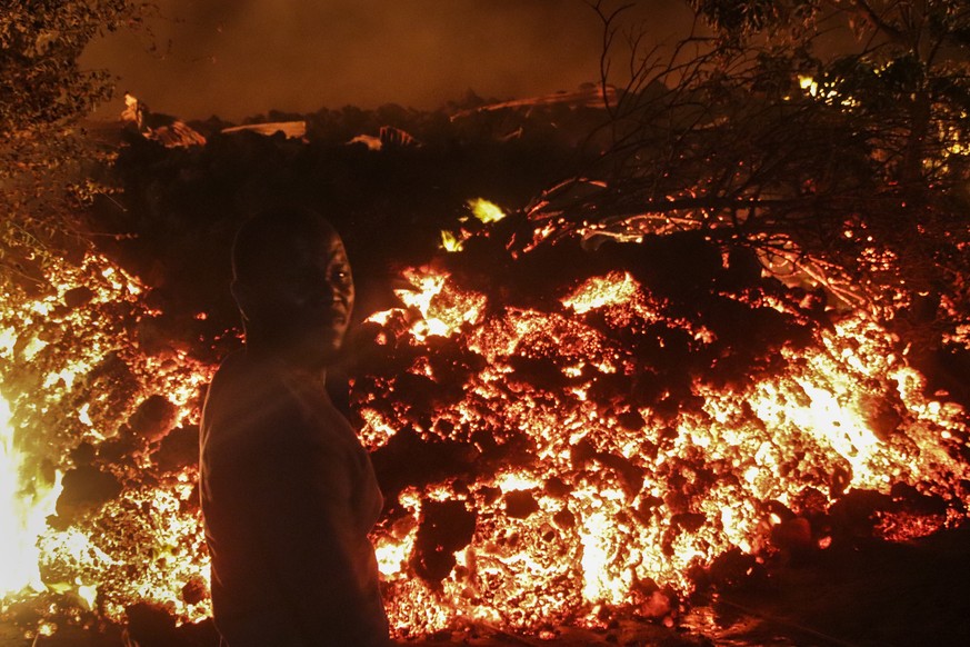 A person stands in front of lava from the eruption of Mount Nyiragongo, in Buhene, on the outskirts of Goma, Congo in the early hours of Sunday, May 23, 2021. Congo&#039;s Mount Nyiragongo erupted for ...