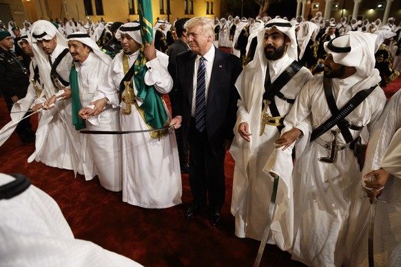 President Donald Trump holds a sword and sways with traditional dancers during a welcome ceremony at Murabba Palace, Saturday, May 20, 2017, in Riyadh. (AP Photo/Evan Vucci)