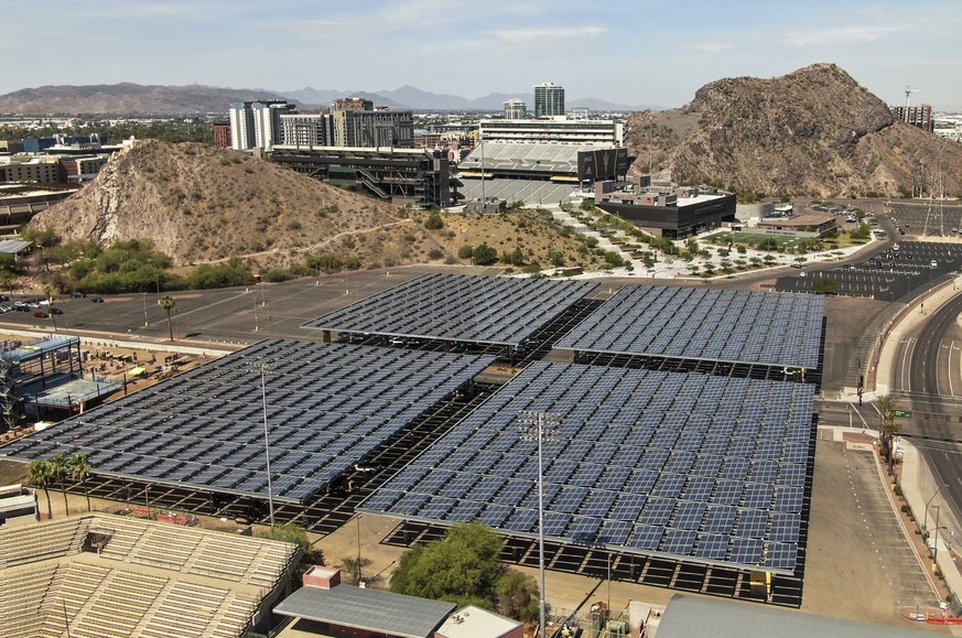 epa09329679 An aerial photo made with a drone shows solar panels placed above parking spaces on the campus of Arizona State University in Tempe, Arizona, USA, 07 July 2021. The panels not only capture ...