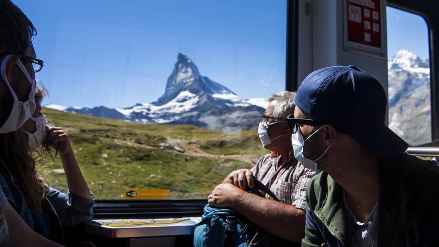 Des touristes portant un masque de protection descendent du Gornergrat au village de Zermatt dans le train du chemin de fer du Gornergrat devant le Cervin pendant la crise du Coronavirus (Covid-19) a  ...