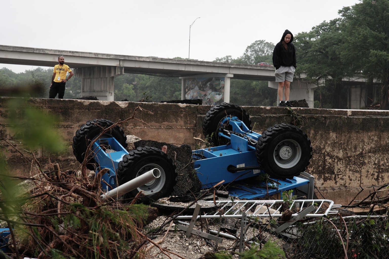 epa12219269 People view a construction vehicle amongst flood debris in the Guadalupe River, in Kerrville, Texas, USA, 05 July 2025. Early 04 July, floodwaters swept through a summer camp and nearby ho ...