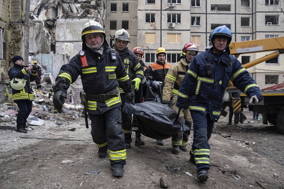 Rescue workers carry the body of a man who was killed in a Russian missile strike on an apartment building in the southeastern city of Dnipro, Ukraine, Monday, Jan. 16, 2023. (AP Photo/Evgeniy Malolet ...