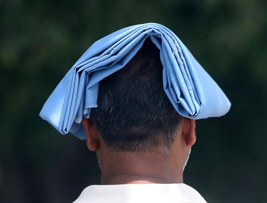 epa09920059 A man walks with his head covered against the sun during a hot afternoon on the outskirts of New Delhi, India, 01 May 2022. According to the India Meteorological Department (IMD), Delhi an ...