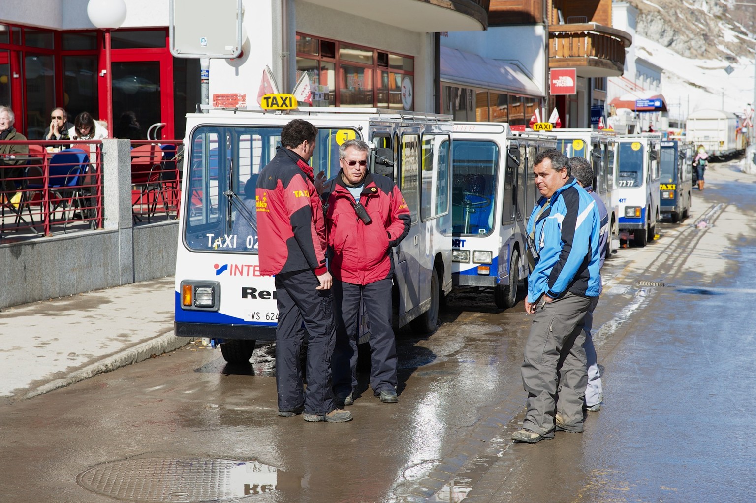 Electric taxi drivers talk at the parking lot in Zermatt, Switzerland., ZERMATT, SWITZERLAND - MARCH 03, 2009: Unidentified electric taxi drivers talk at the parking lot in Zermatt, Switzerland. To pr ...