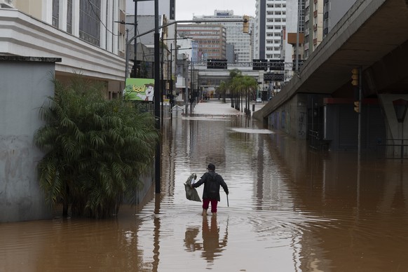 epa11316996 A man wades in a flooded street in the center of Porto Alegre, Brazil, 03 May 2024. Regional authorities reported that at least 37 people died and 60 are missing as a result of heavy rains ...