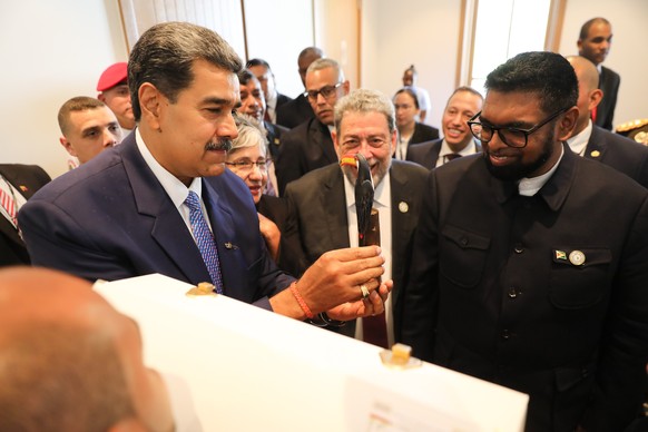 epa11191979 A handout photo made available by Prensa Miraflores shows the Presidents of Venezuela Nicolas Maduro (L) and of Guyana Irfaan Ali (R) in an exchange of gifts during a meeting in which they ...