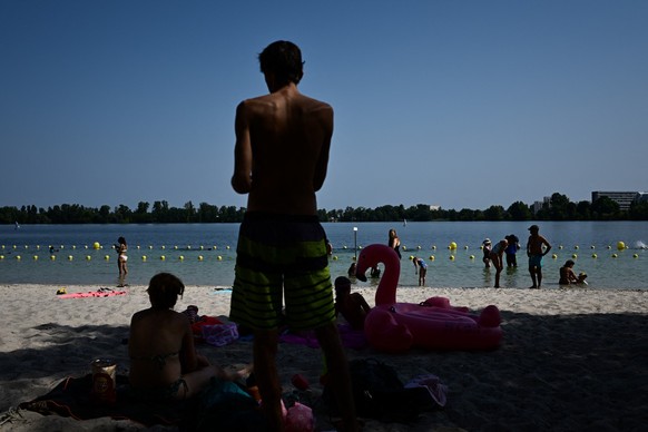 Visitors sit in the shade on the sandy shore of Bordeaux Lac, a man-made lake in the north of the city, in Bordeaux, southwestern France on August 10, 2025, as a heatwave spreads across southern areas ...