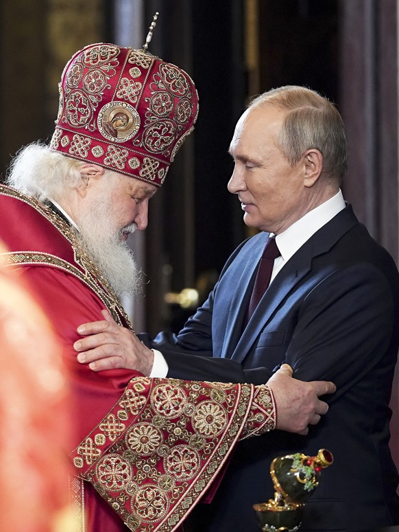 In this handout photo released by Russian Orthodox Church Press Service, Russian Orthodox Church Patriarch Kirill, left, and Russian President Vladimir Putin congratulate each other after the Easter s ...