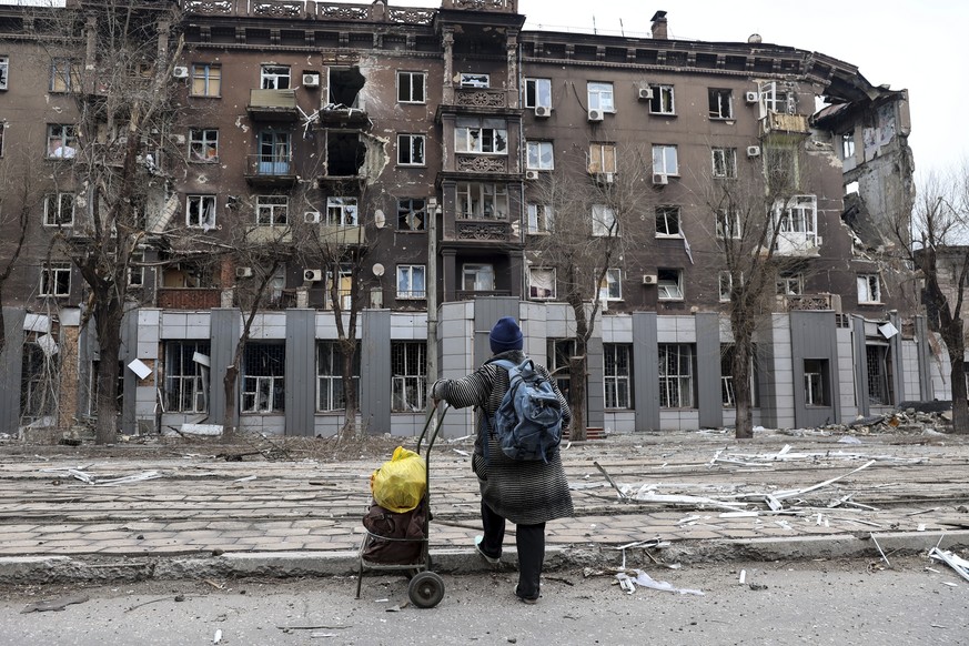FILE - A local resident looks at a damaged during a heavy fighting apartment building near the Illich Iron &amp; Steel Works Metallurgical Plant, the second largest metallurgical enterprise in Ukraine ...